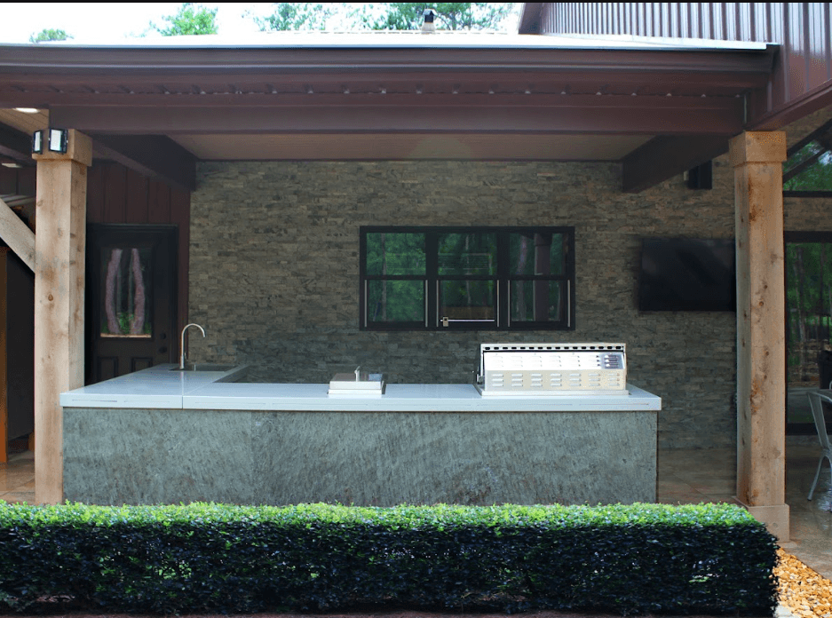 Outdoor kitchen view with grill and seating area.